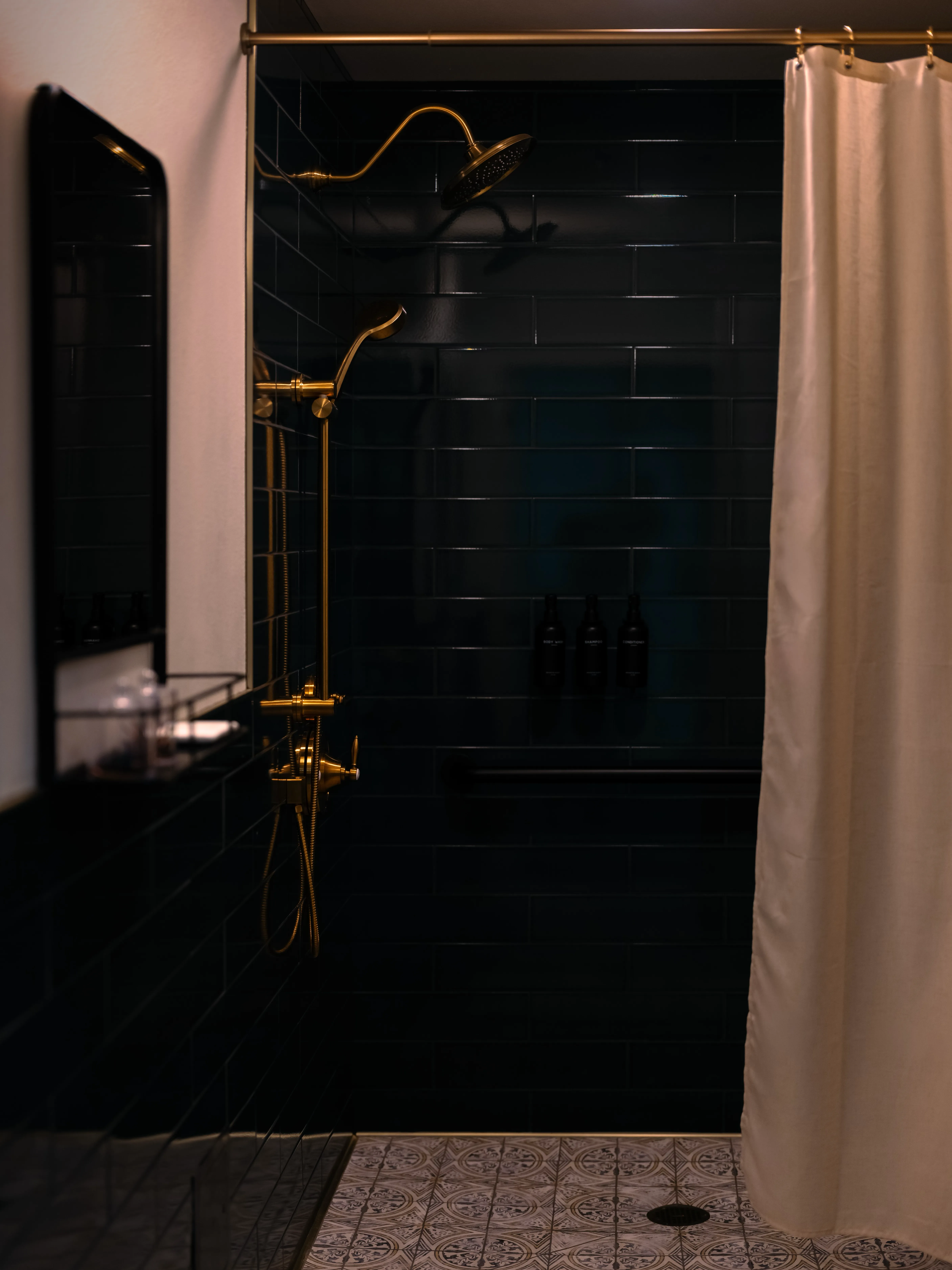 A private shower with deep green tile and brass fixtures